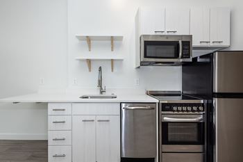 A modern kitchen with stainless steel appliances and white cabinetry.